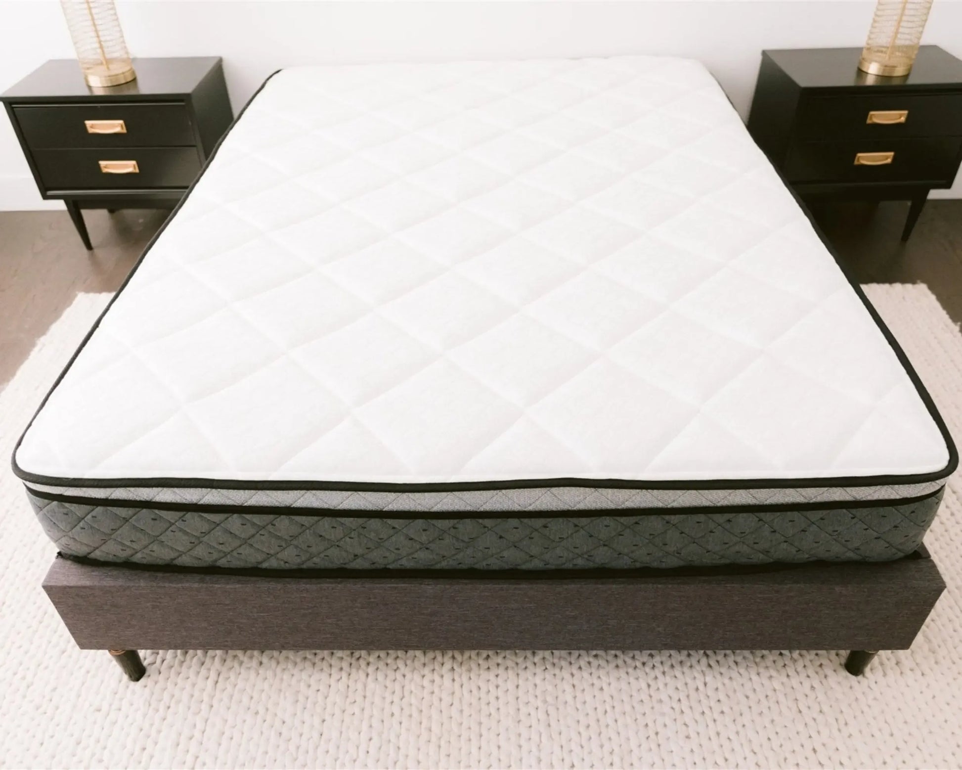 Mattress on a bed frame with two nightstands in the background
