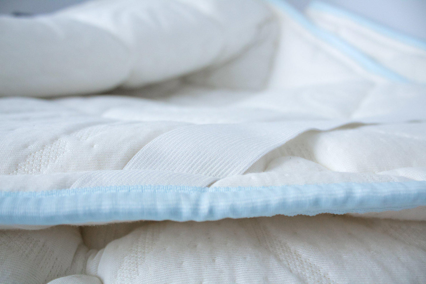 Close up Haven Mattress topped on a Haven Mattress bed-in-box showing the light blue edging and mattress strap